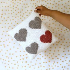 a hand holding a pillow with hearts on it