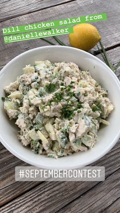 a white bowl filled with chicken salad on top of a wooden table next to a lemon