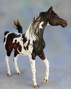 a black and white toy horse standing on its hind legs in front of a blue background