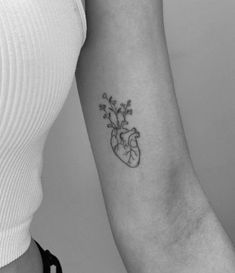 a woman's arm with a heart and flowers tattoo on the left inner arm