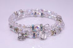 "These stunning custom made Memory Wire Rosary Bracelets are made using Czech Fire-Polished Arora Borealis Crystal glass, pearlized glass, Hemalyke or blue spot stone 6 mm beads and Czech Fire-Polished Arora Borealis Crystal glass \"Our Father\" beads with beautiful iridescent rondelles on either side of it. A tiny Our Lady of Guadalupe-Divine Mercy medal and a small, round Benedictine crucifix are on either end. This full rosary is the perfect piece of Catholic jewelry for yourself, RCIA Candid Mini Rosaries, Memory Wire Jewelry, Praying The Rosary, Memory Wire Bracelet, Catholic Jewelry, Rosary Bracelet, Divine Mercy, Our Father, Memory Wire Bracelets