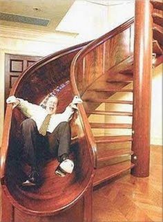 a man sitting on top of a wooden stair case in front of a spiral staircase