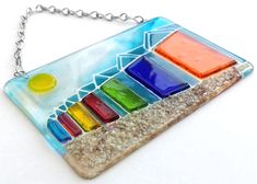 a multicolored stained glass pendant hangs from a chain on a white table top