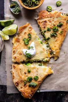 two slices of quesadilla on parchment paper with salsa and limes in the background