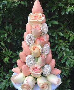 a cake with flowers on top of it in the shape of a pyramid, and surrounded by greenery