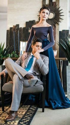 a man sitting on a chair next to a woman in a blue dress and tie