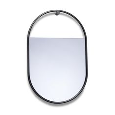 an oval mirror hanging on the wall with a black metal ring around it's edge