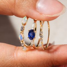 a woman's hand holding two gold rings with blue and white stones