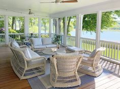 a screened porch with wicker furniture on the deck and water in the backround