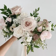 a bouquet of pink and white flowers being held by someone's hand