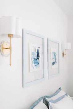 two framed pictures hang on the wall above a bed with blue and white pillows in a bedroom