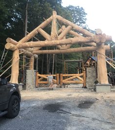 a man standing in front of a wooden structure with logs on it's sides