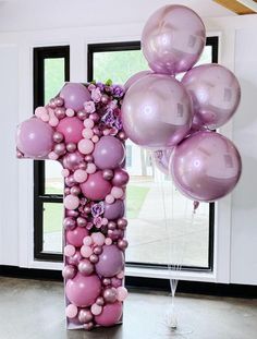 the balloon column is decorated with pink and purple balloons, while flowers are arranged around it