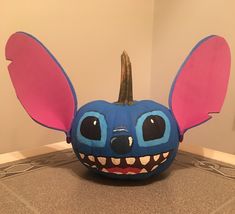 a blue pumpkin with pink ears on it's head and eyes painted to look like stitchers