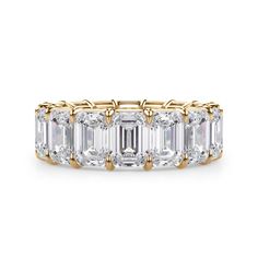 an emerald - cut diamond ring set in yellow gold with baguetts on each side