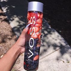 a person holding up a can of soda with strawberries on the top and bottom