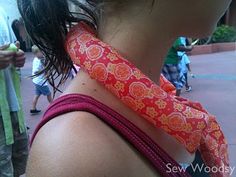 a woman with a tie on her neck in the sun at an amusement park,