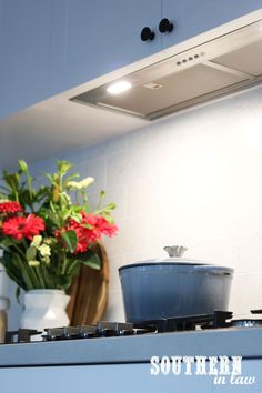 a pot on top of a stove in a kitchen next to a vase with flowers