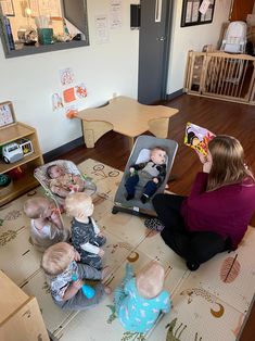 a woman is sitting on the floor with her baby and several other babies in front of her