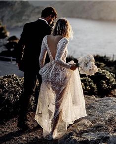 a man and woman standing next to each other on top of a hill near the ocean