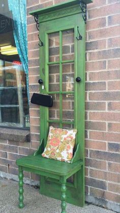 a green bench sitting next to a window on the side of a brick building in front of a store