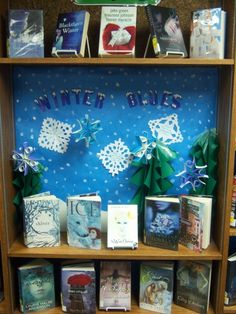 a book shelf filled with lots of books on top of wooden shelves covered in paper snowflakes