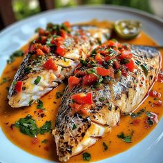 two fish with tomato sauce on a white plate