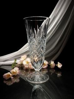 a glass vase sitting on top of a table next to some pink and white flowers