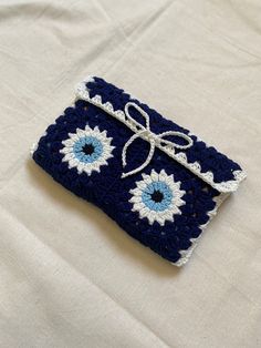 a blue and white crocheted purse with a bow on it's side