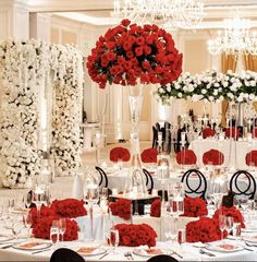 a table set up with red and white flowers, candles and centerpieces for a wedding reception