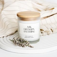 a white candle sitting on top of a table next to a towel and flower pot