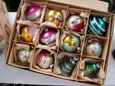 an open cardboard box filled with assorted christmas ornament ornaments on a table