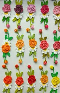 crocheted flowers are arranged in rows on a white surface