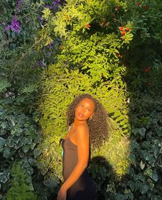 a woman standing in front of some bushes