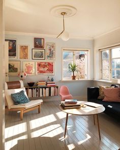 a living room filled with furniture next to a window covered in bookshelves and pictures