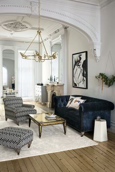 a living room filled with furniture and a chandelier hanging over the top of it