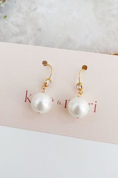 a pair of earrings with pearls on it and the words kate emari written in gold