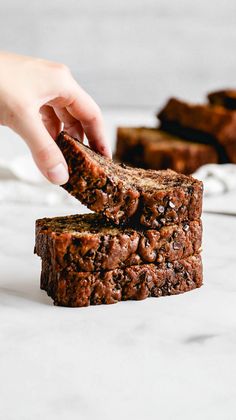 a person is picking up some brownies from the table with one hand on top of them