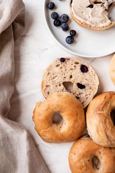 bagels and blueberries on a white plate next to a napkin with a cloth