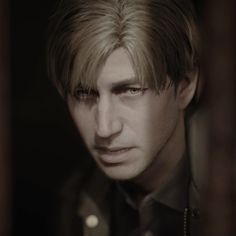 a man with blonde hair and black shirt looking at the camera in a dark room