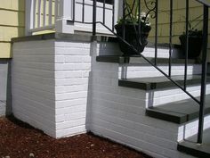 a white brick building with stairs leading up to the front door and flower pots on the steps