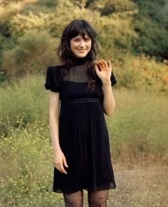 a woman in black dress and tights holding a piece of food up to her face