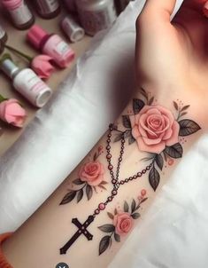 a woman's arm with pink roses on it and a cross in the middle