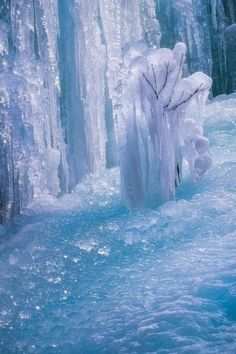 the water is frozen and blue with ice hanging off it's sides that are covered in icicles