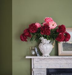 there is a vase with flowers in it on the fireplace mantel next to a mirror