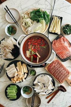 a table topped with lots of food and chopsticks on top of it's sides