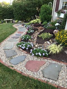 a garden with stones and flowers in front of a house