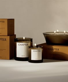 three candles sitting on top of boxes next to each other and one candle is lit