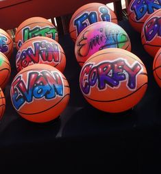 several basketballs with graffiti on them sitting in front of a bench