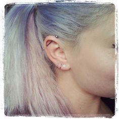 a woman with pink hair and piercings on her ear